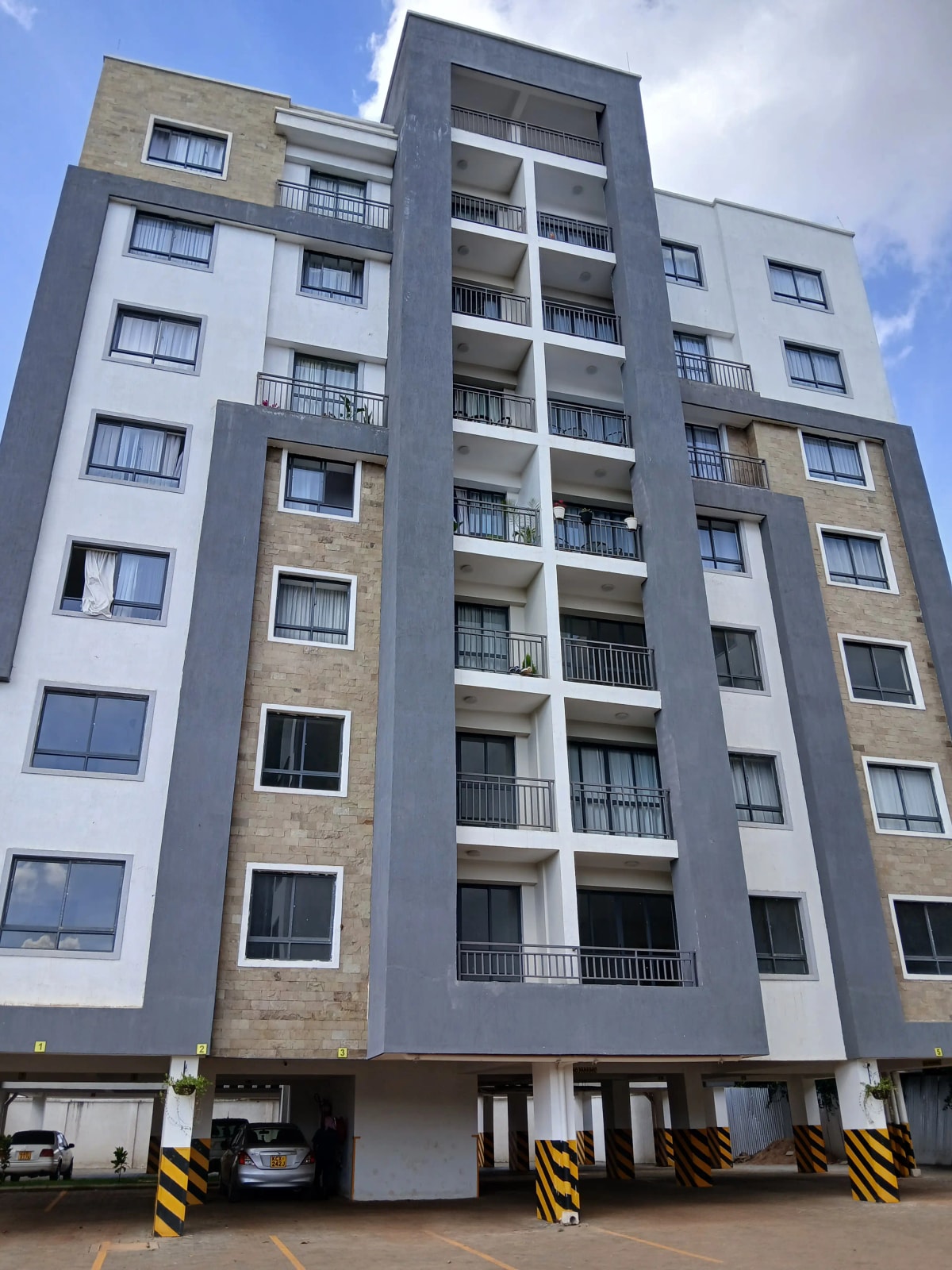 Modern multi-story residential building with balconies and parking