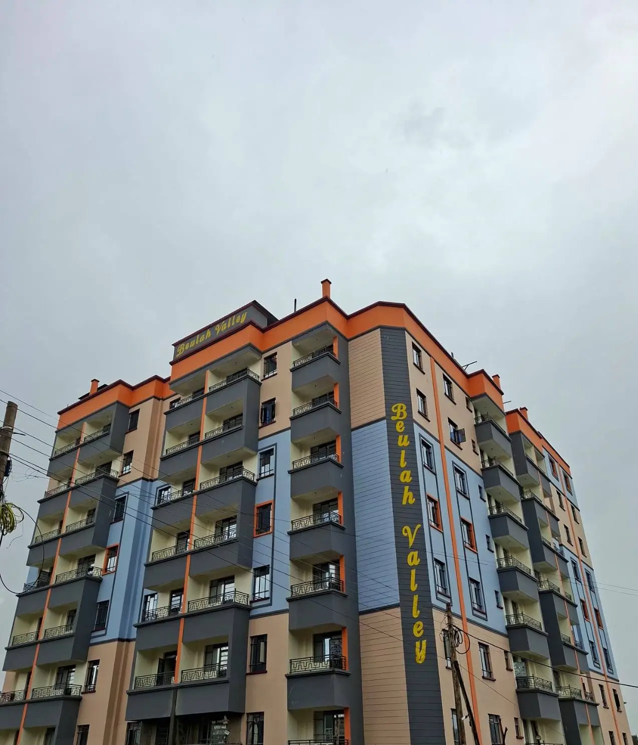 Multi-story residential building with orange roof and balconies.