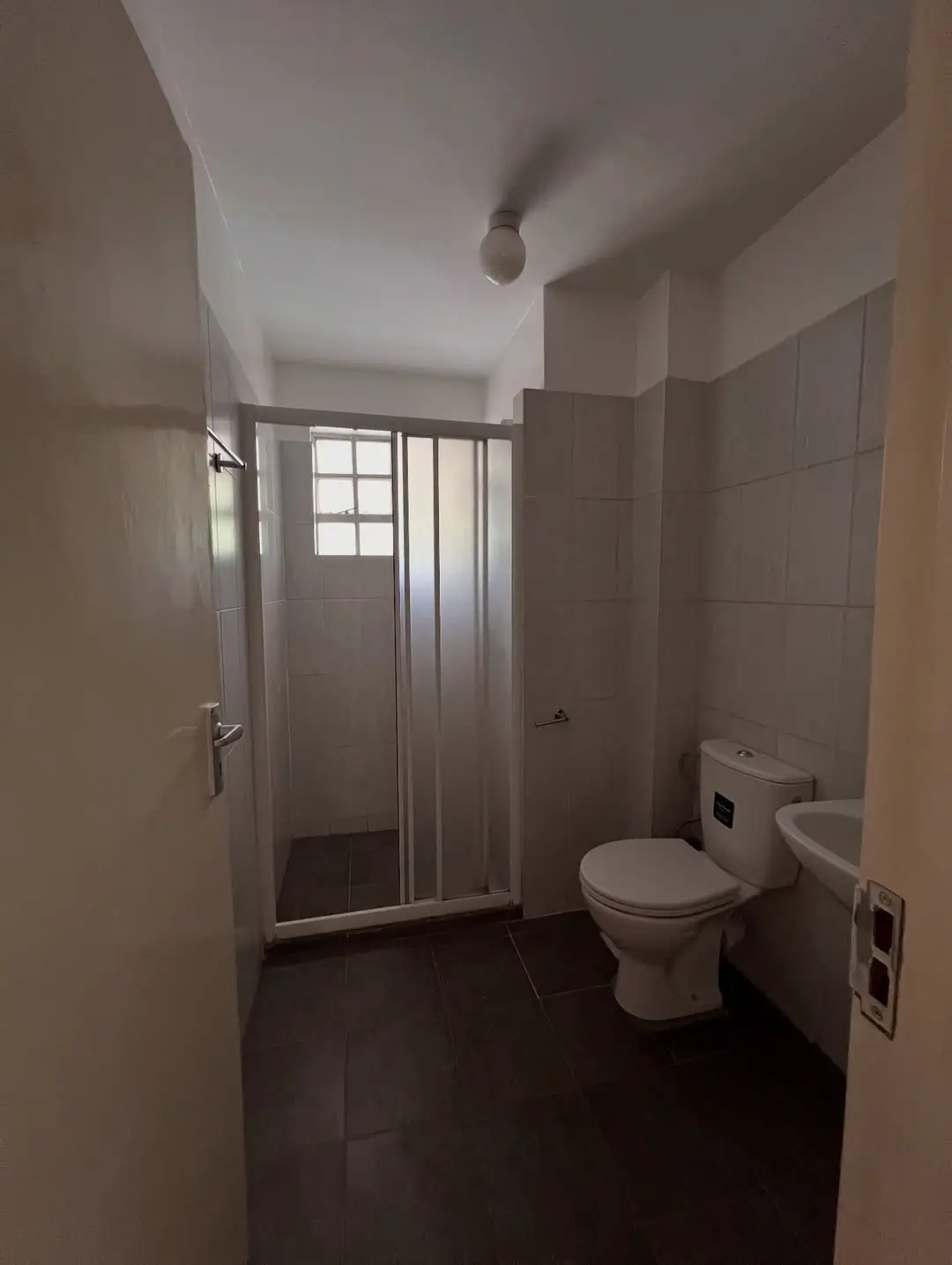 Modern bathroom with toilet, shower enclosure, and window