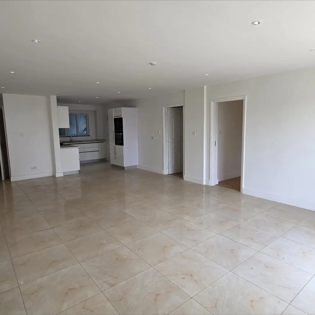 Spacious open-plan living area with kitchen visible in background