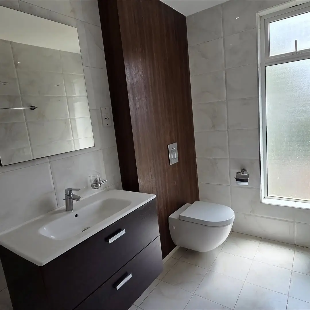 Modern bathroom with dark vanity, wall-mounted toilet, large window