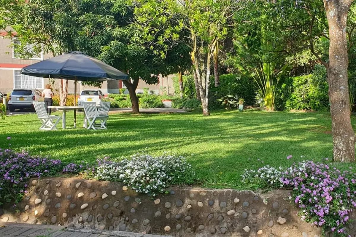 Lush manicured lawn with flowering borders and mature trees