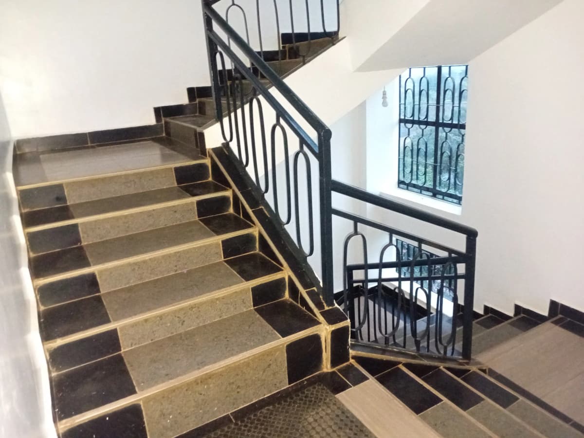 Interior staircase with black metal railing and stone steps.