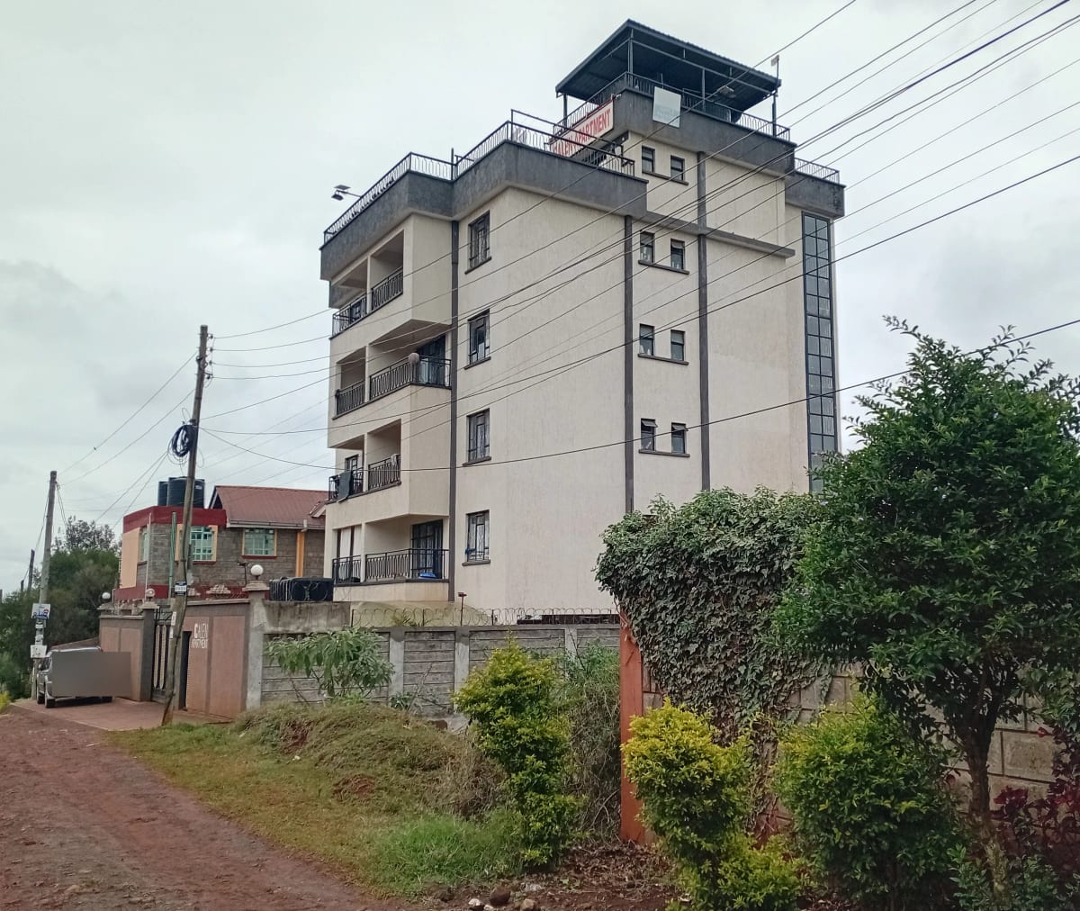 Modern multi-story residential building with balconies and compound walls