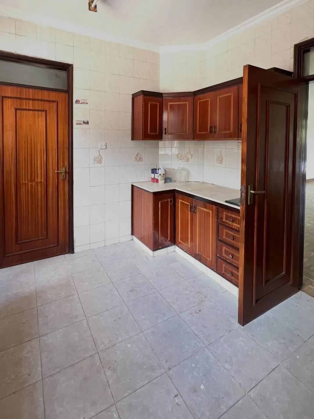 Compact kitchen with wooden cabinets and white tile flooring