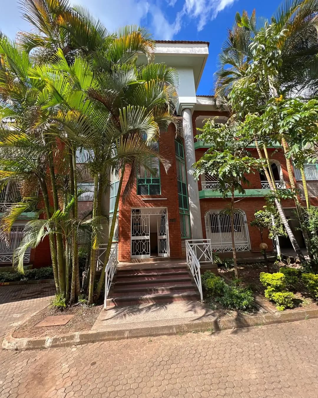 Red brick facade with mature palm trees and manicured compound