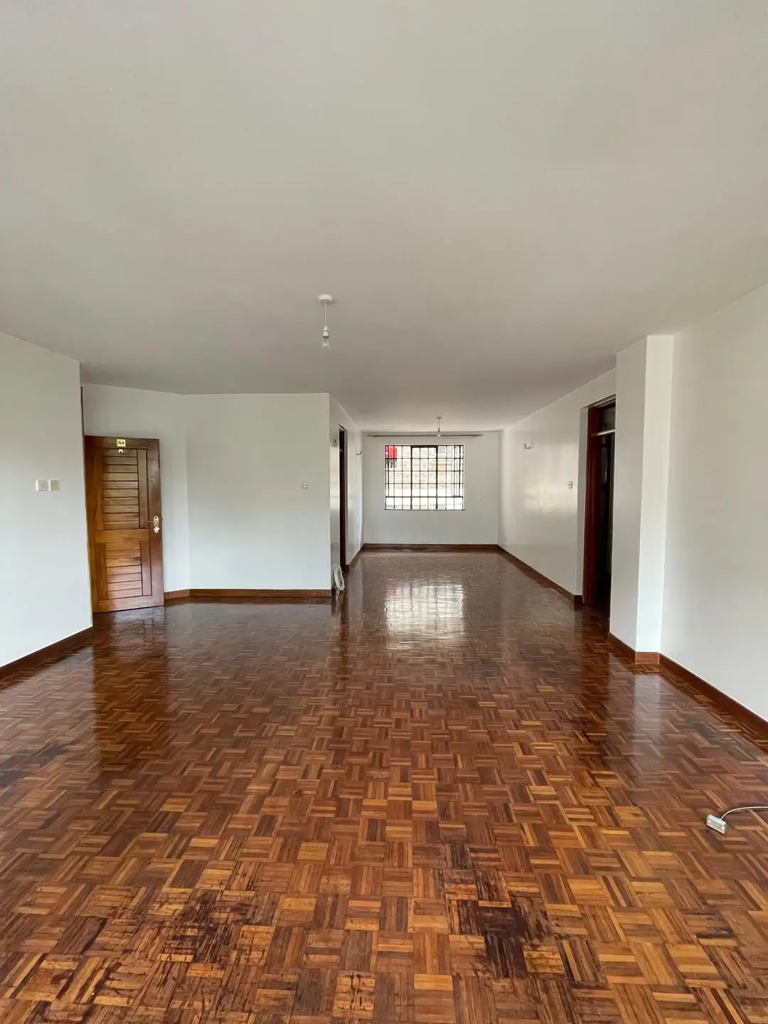 Spacious empty living room with parquet flooring and natural light