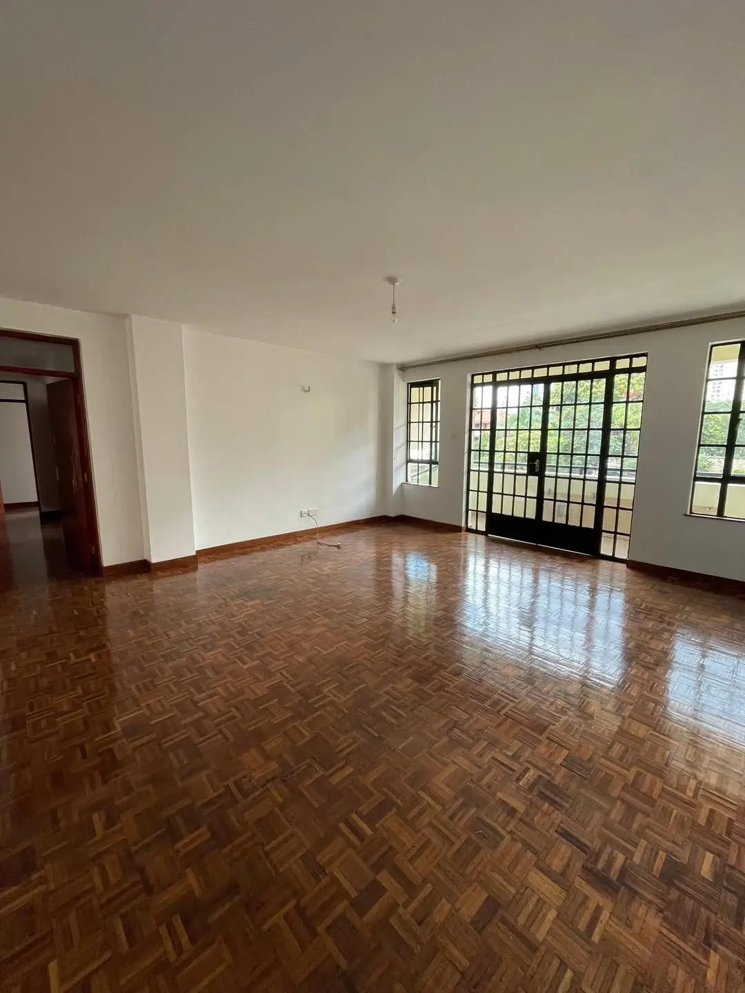 Spacious empty living room with herringbone wooden flooring