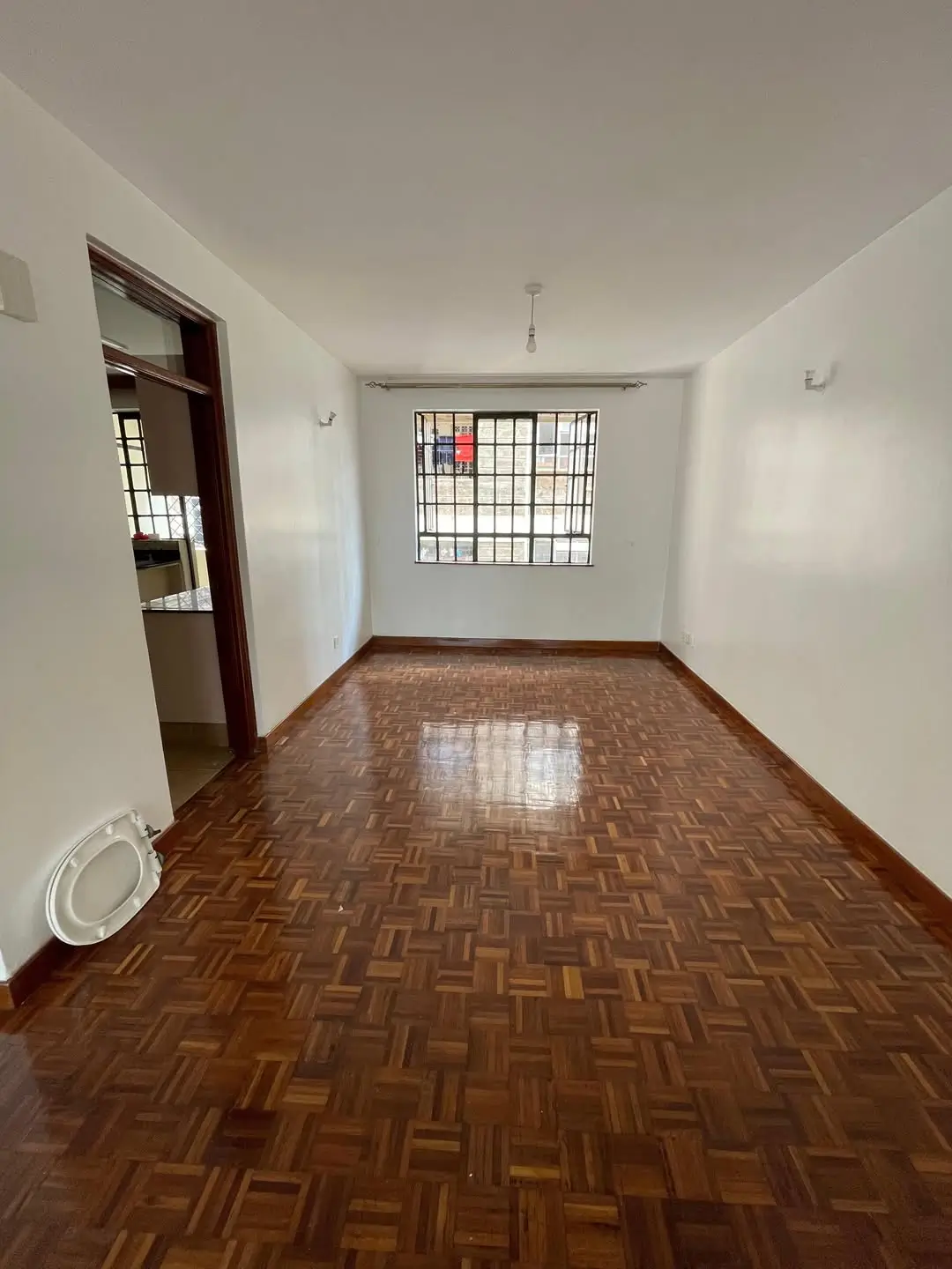 Spacious dining room with herringbone wood floor and barred window