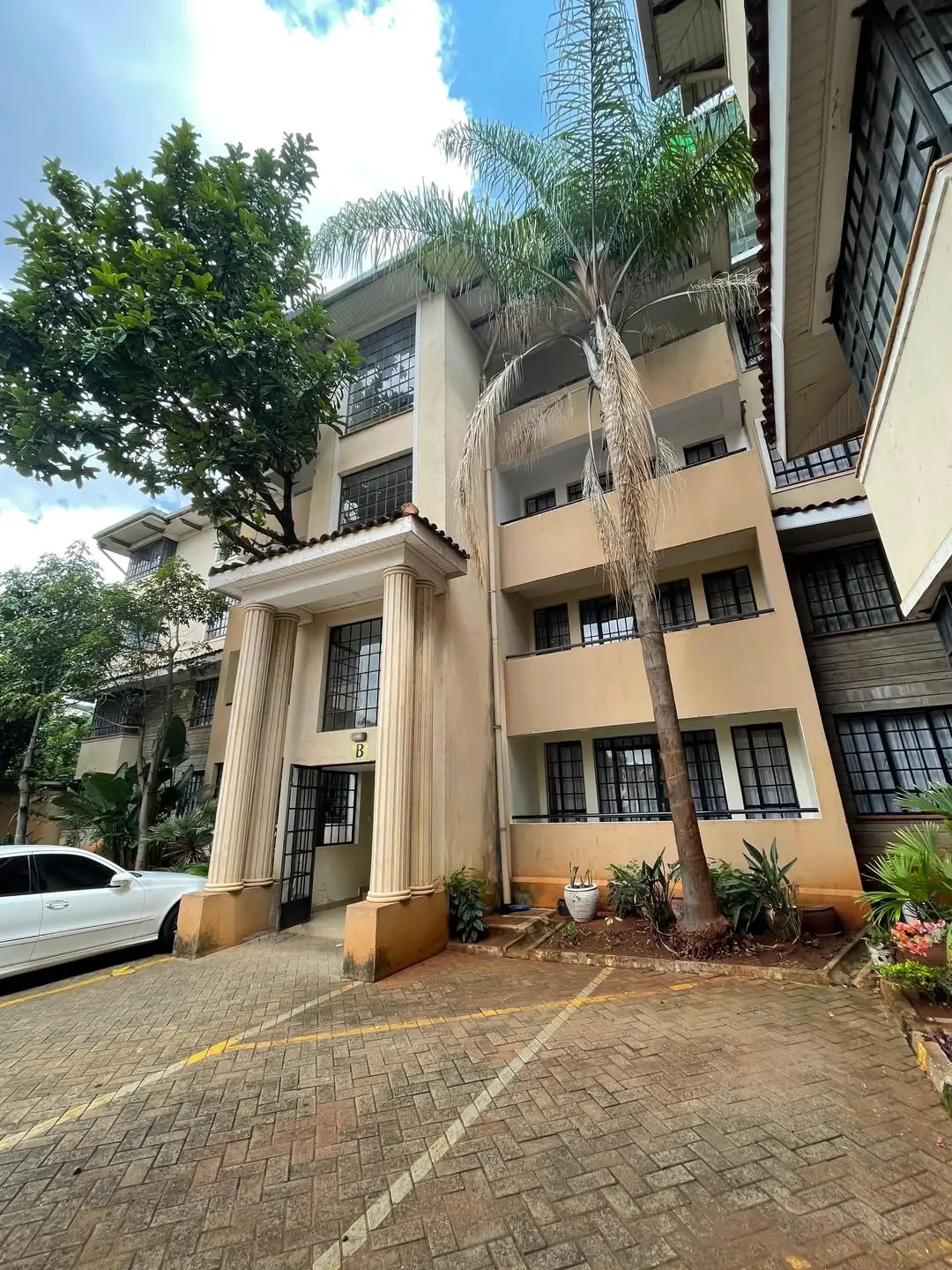 Multi-story residential building with paved driveway and landscaping