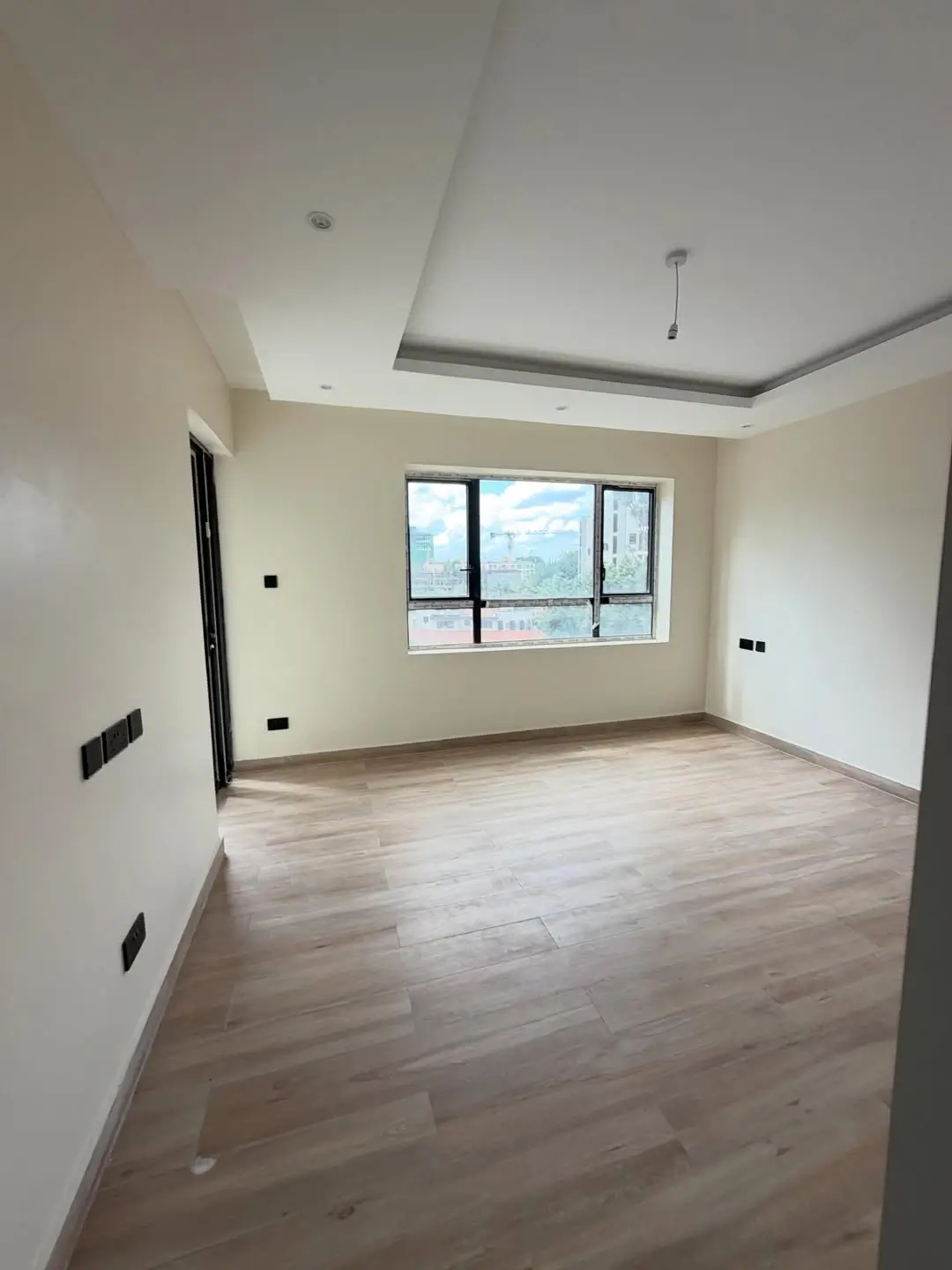 Spacious empty living room with wooden flooring and city view