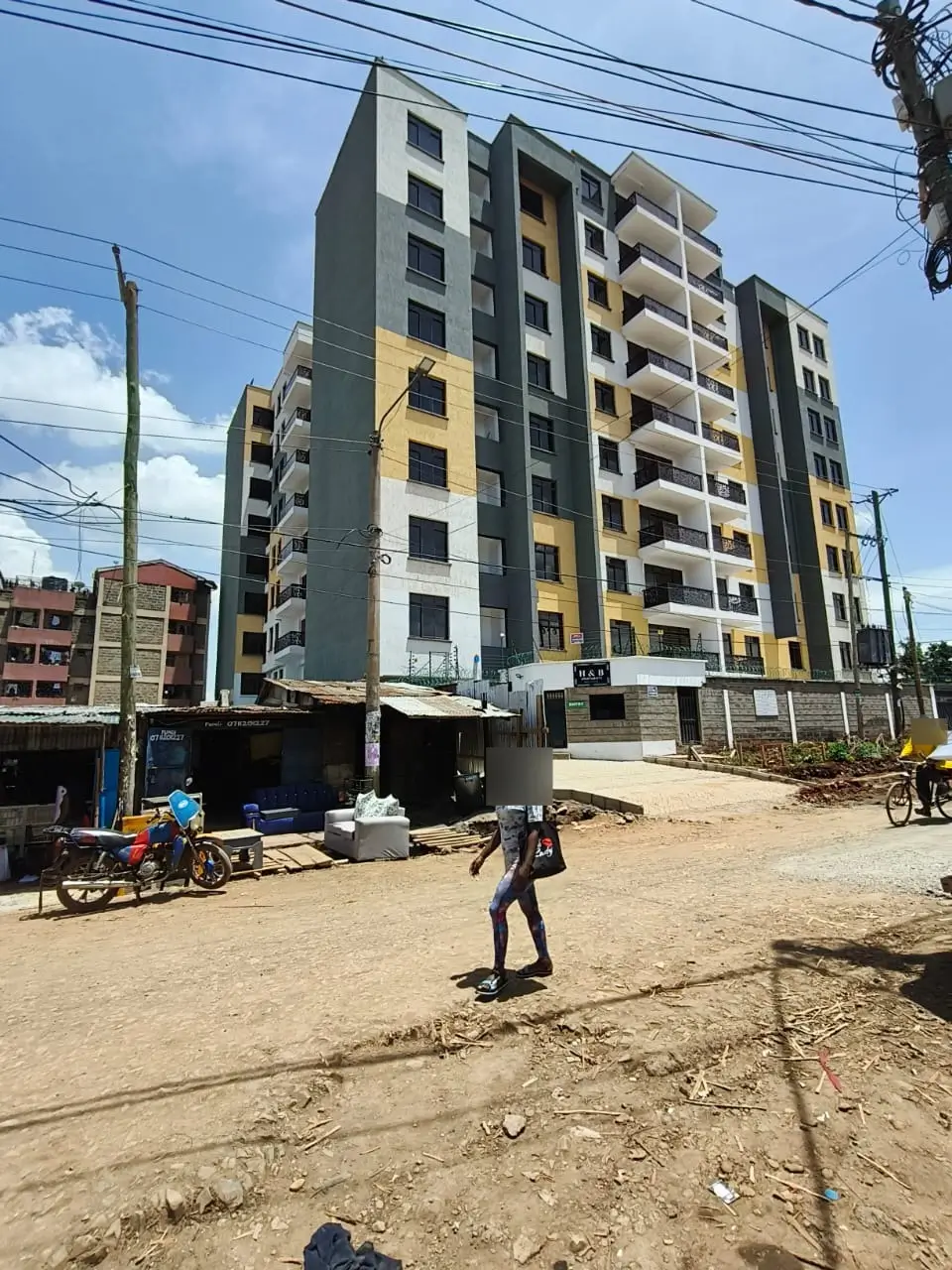 Modern multi-story apartment building with yellow and gray facade