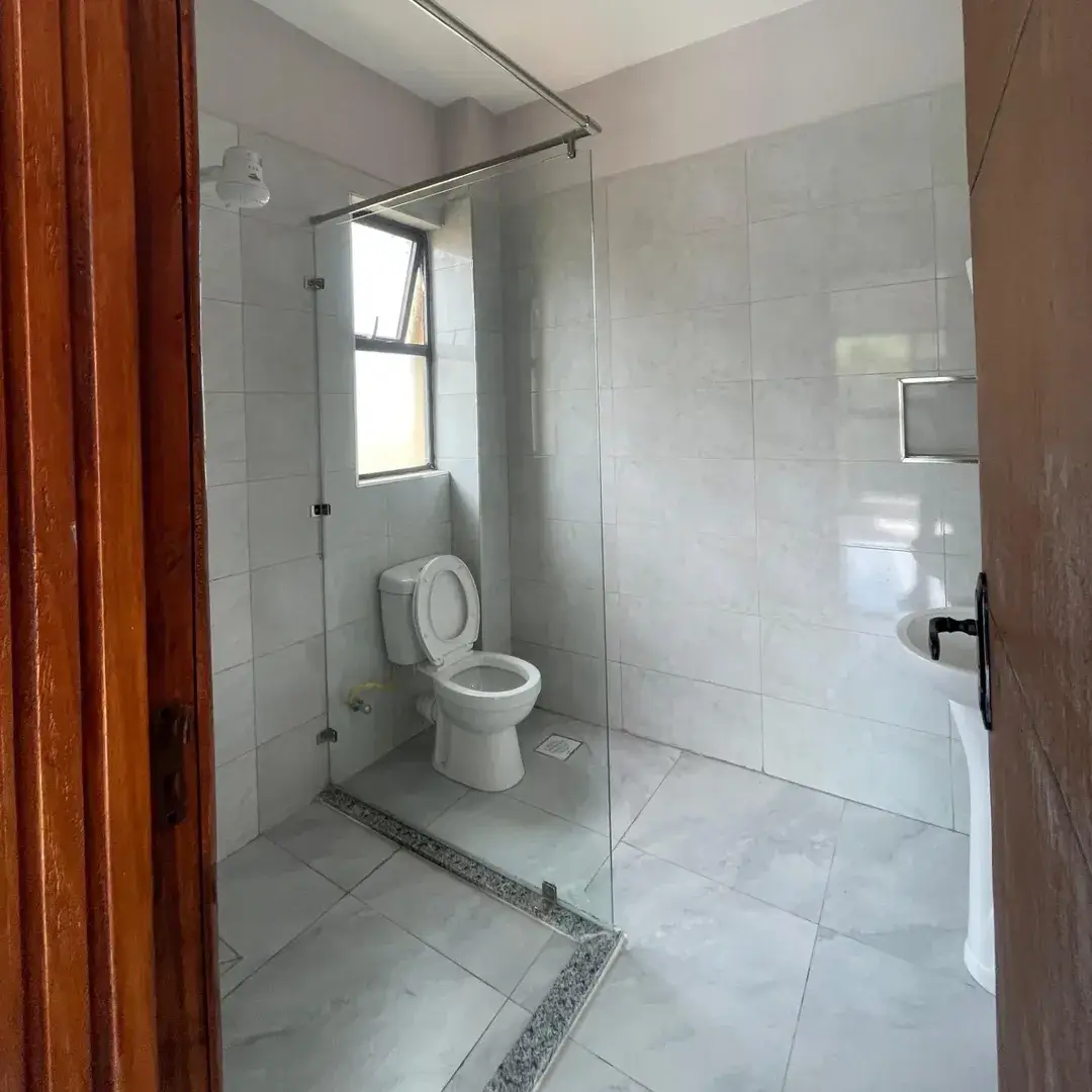 Modern bathroom with glass shower enclosure, toilet, and window