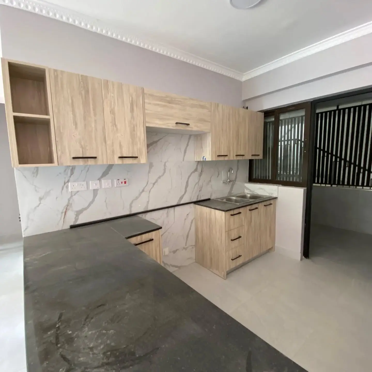 Modern kitchen with marble backsplash, wooden cabinets, dark countertops