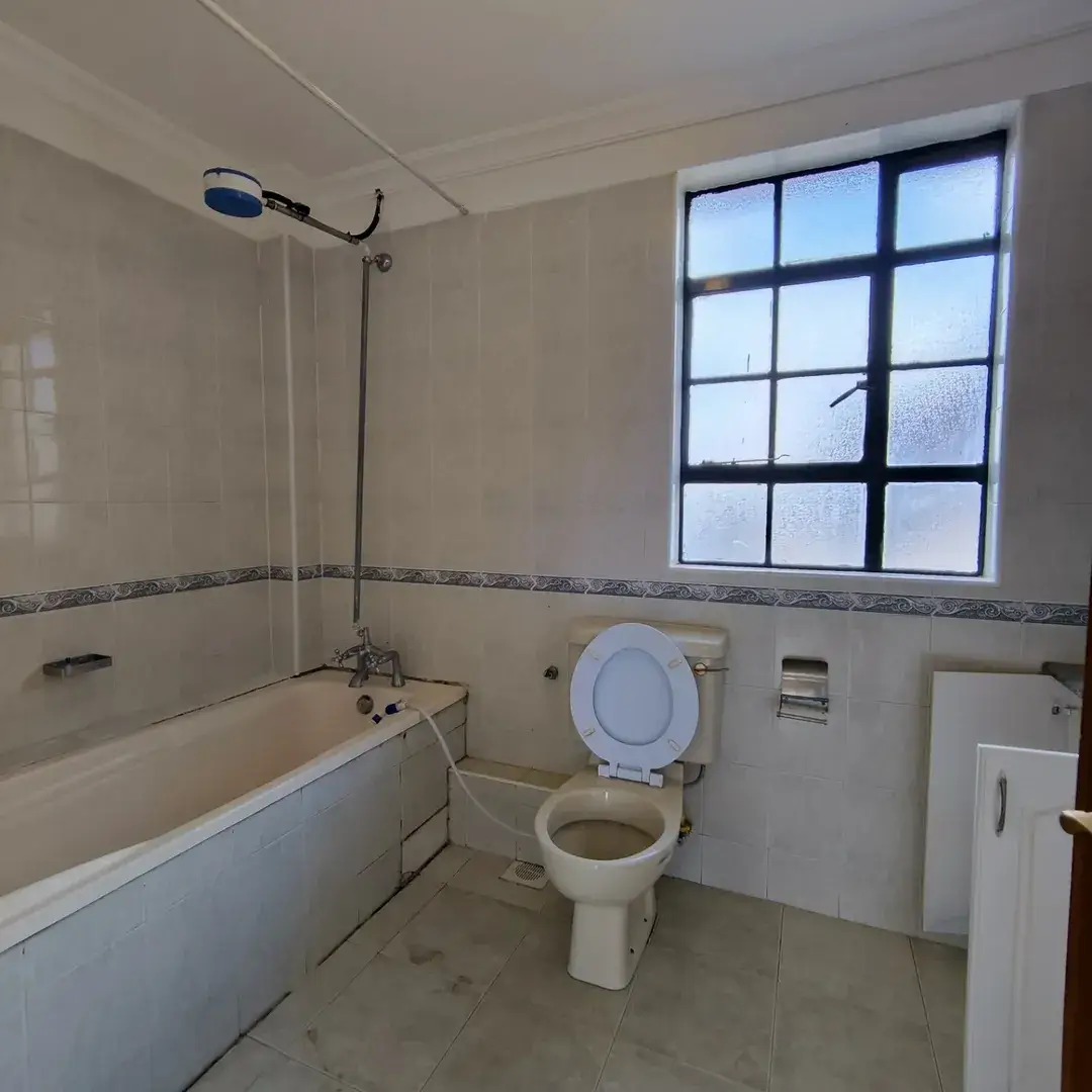 Bathroom with bathtub, toilet, and large window