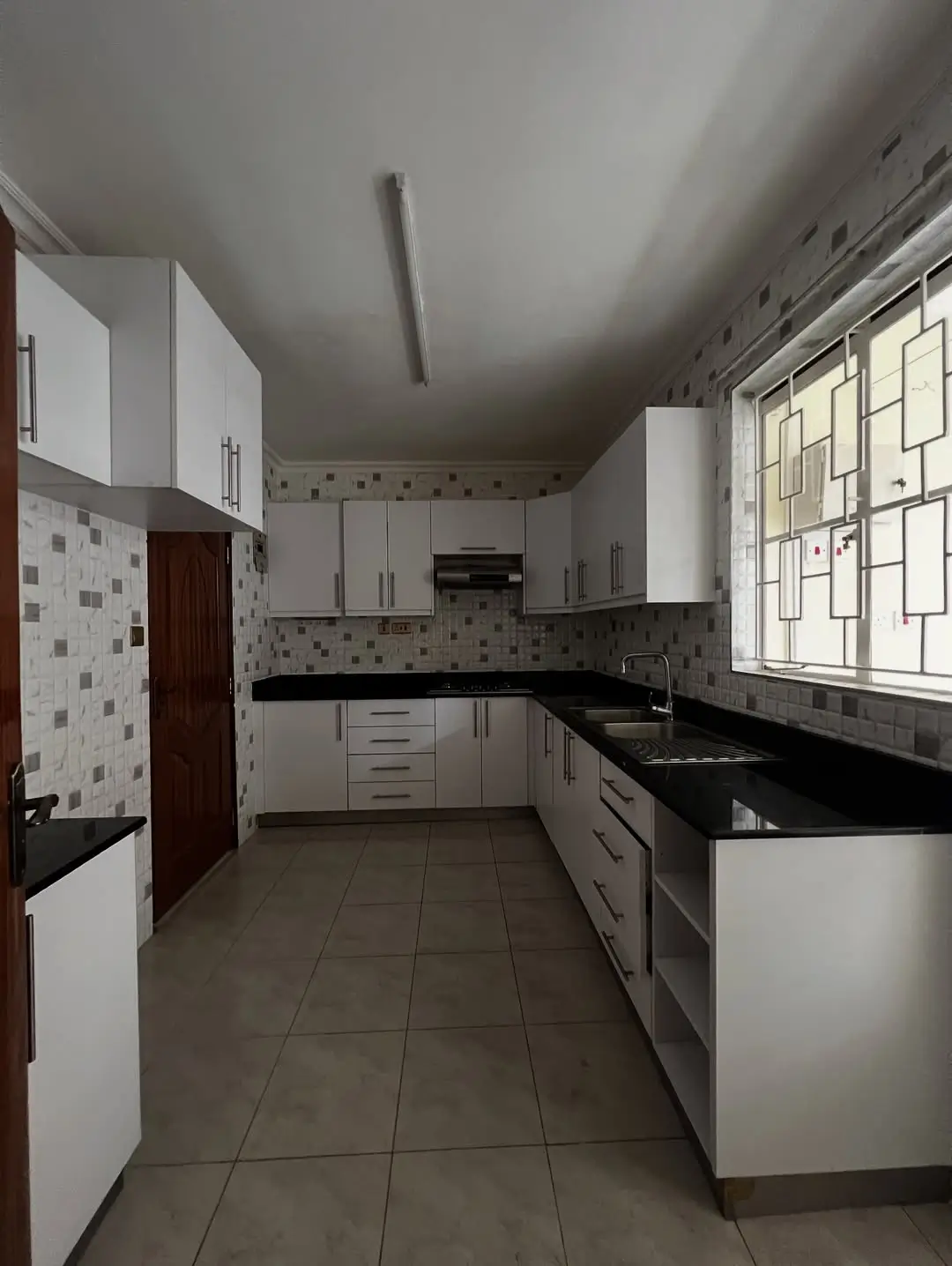 Spacious galley kitchen with white cabinets and black countertops