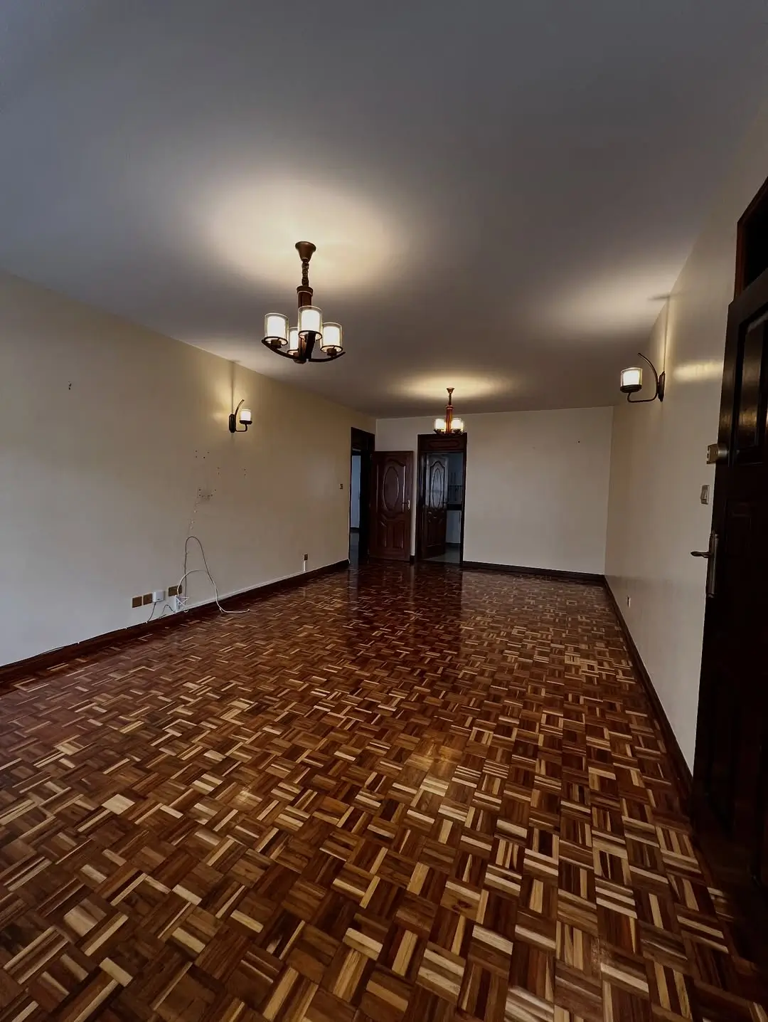 Spacious hallway with herringbone wood flooring and pendant lighting