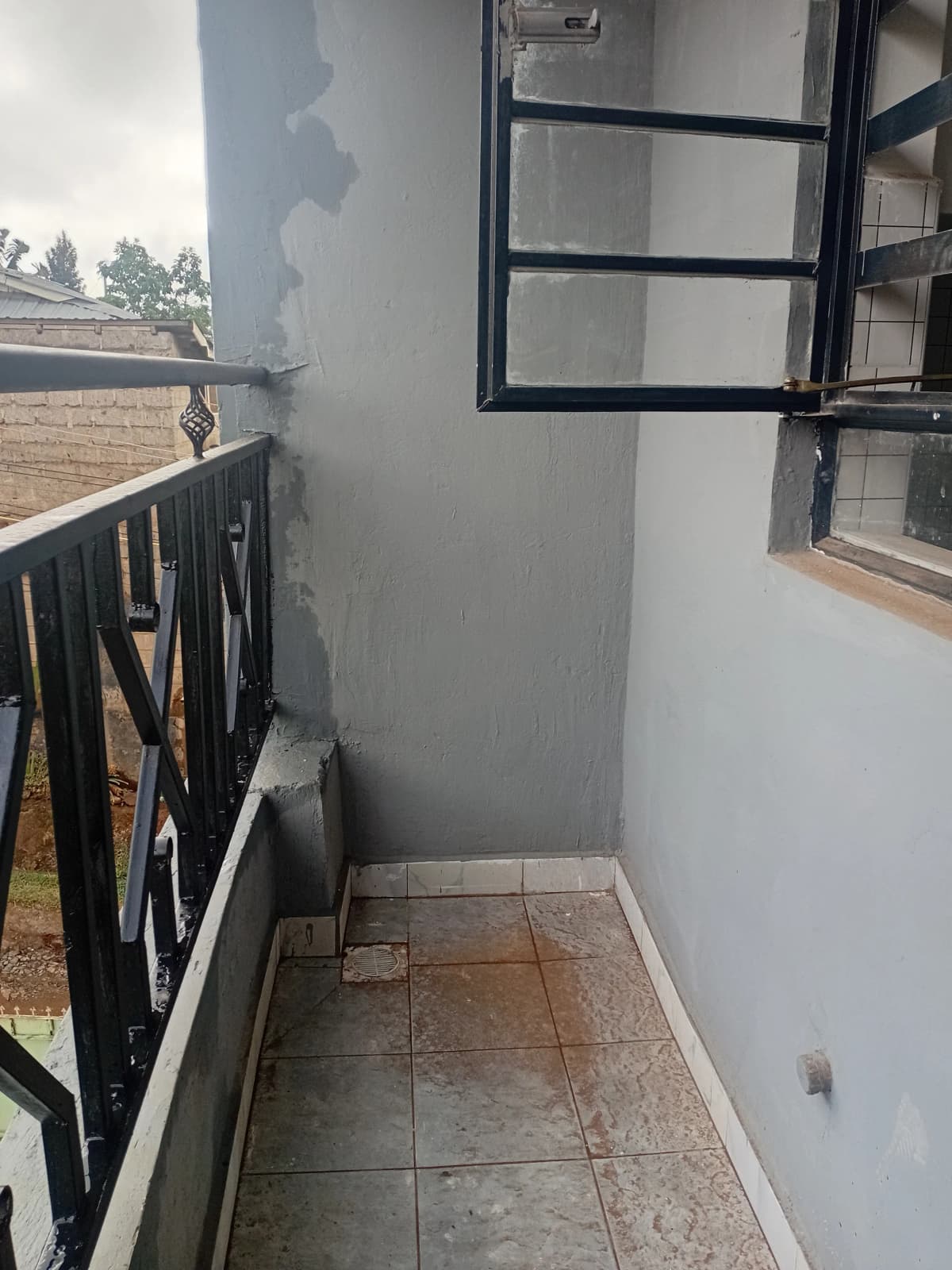 Narrow balcony with black metal railing and tiled flooring