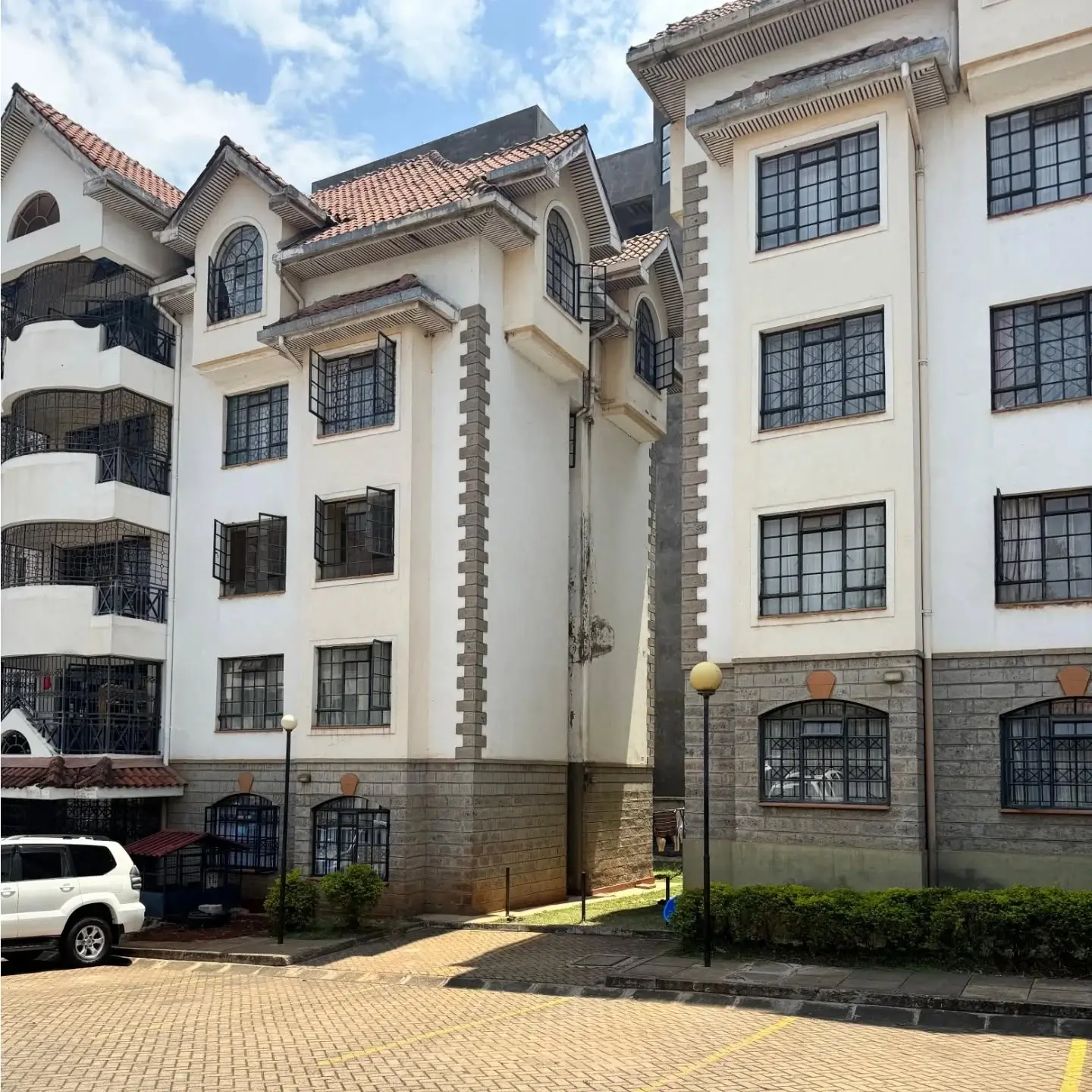 Multi-story residential building with cream facade and tiled compound