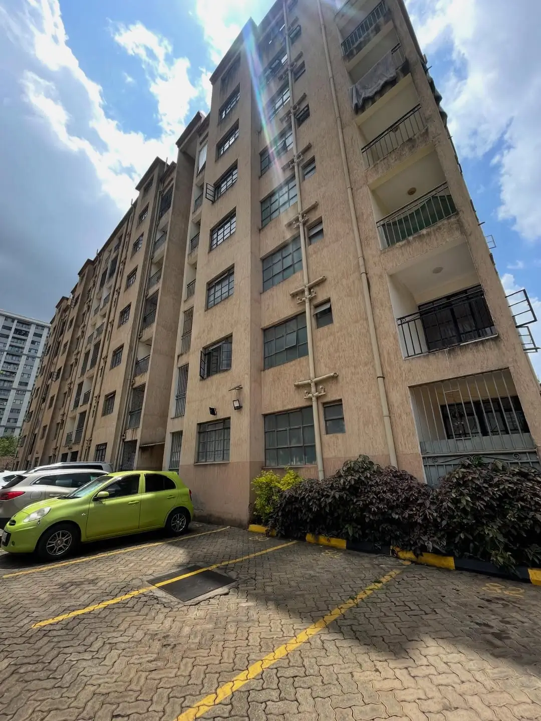 Multi-story residential building facade with parking area