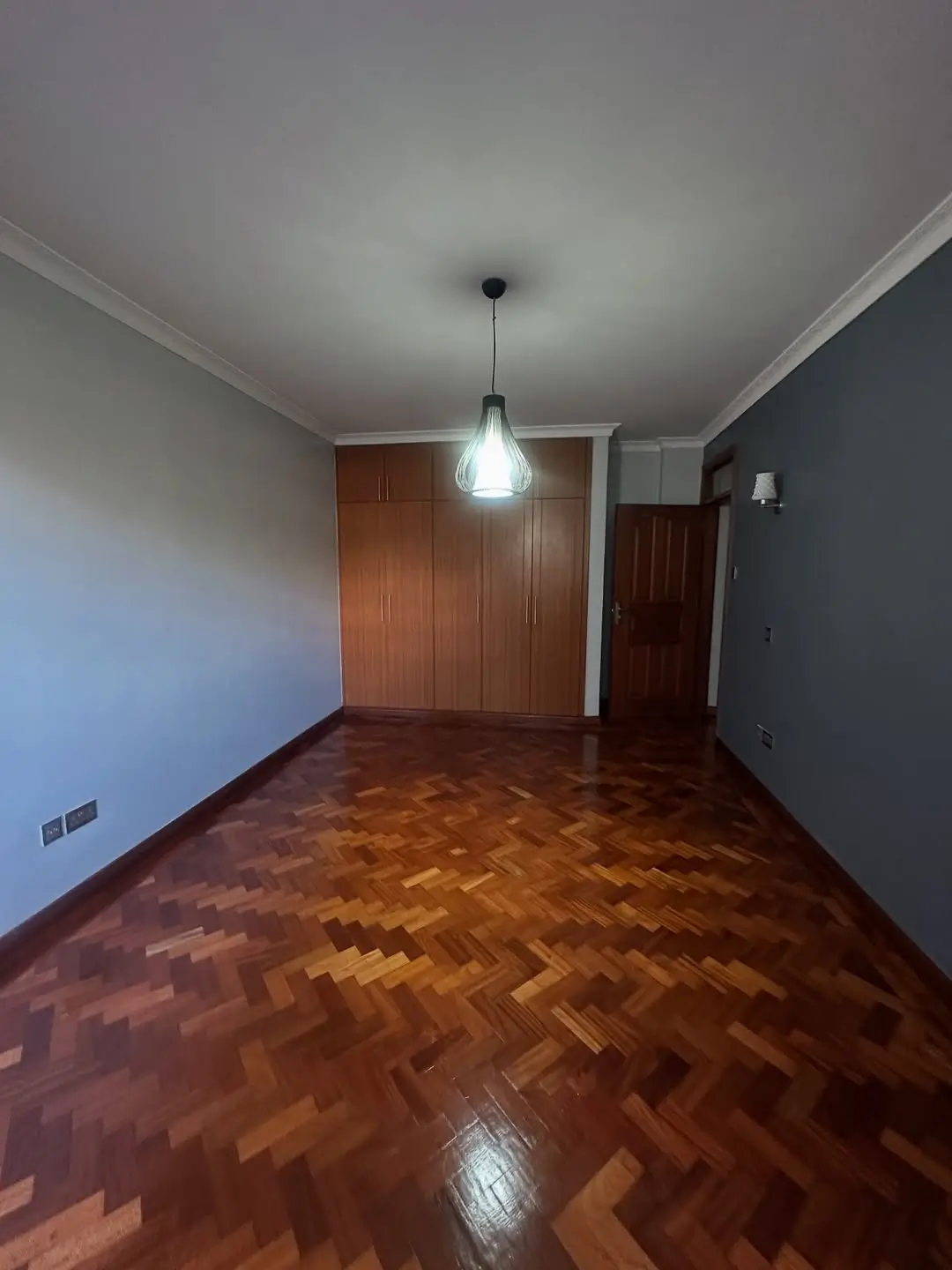 Empty bedroom with herringbone parquet flooring and pendant light