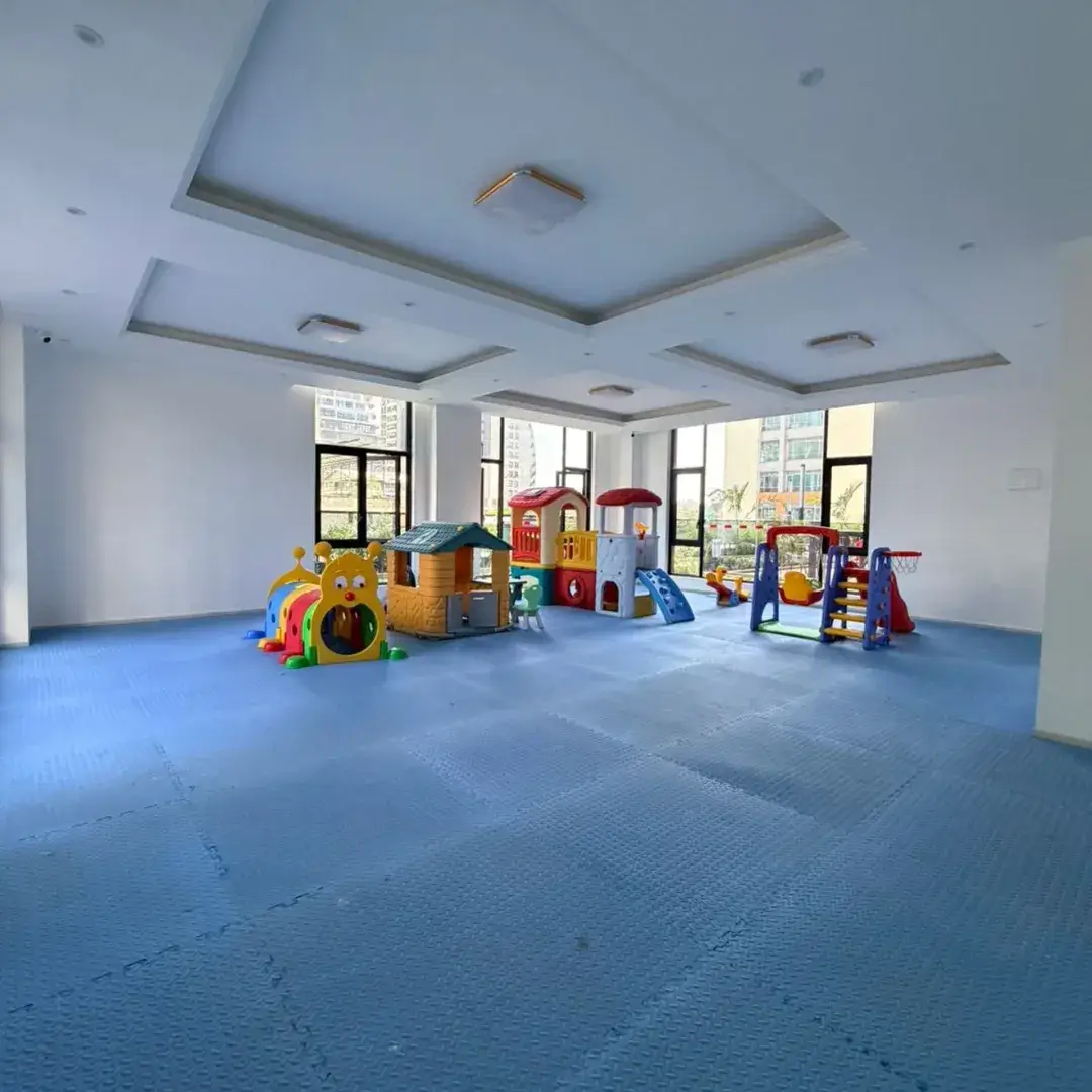 Large empty room with children's play equipment and blue flooring