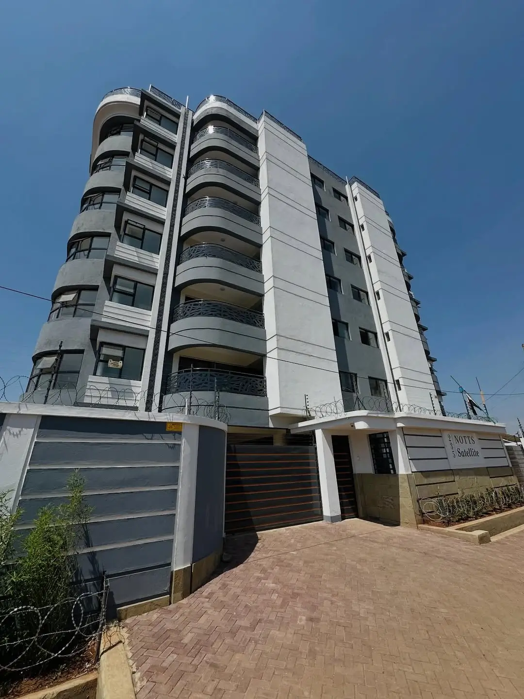 Modern mid-rise apartment building with curved balconies and ground gate