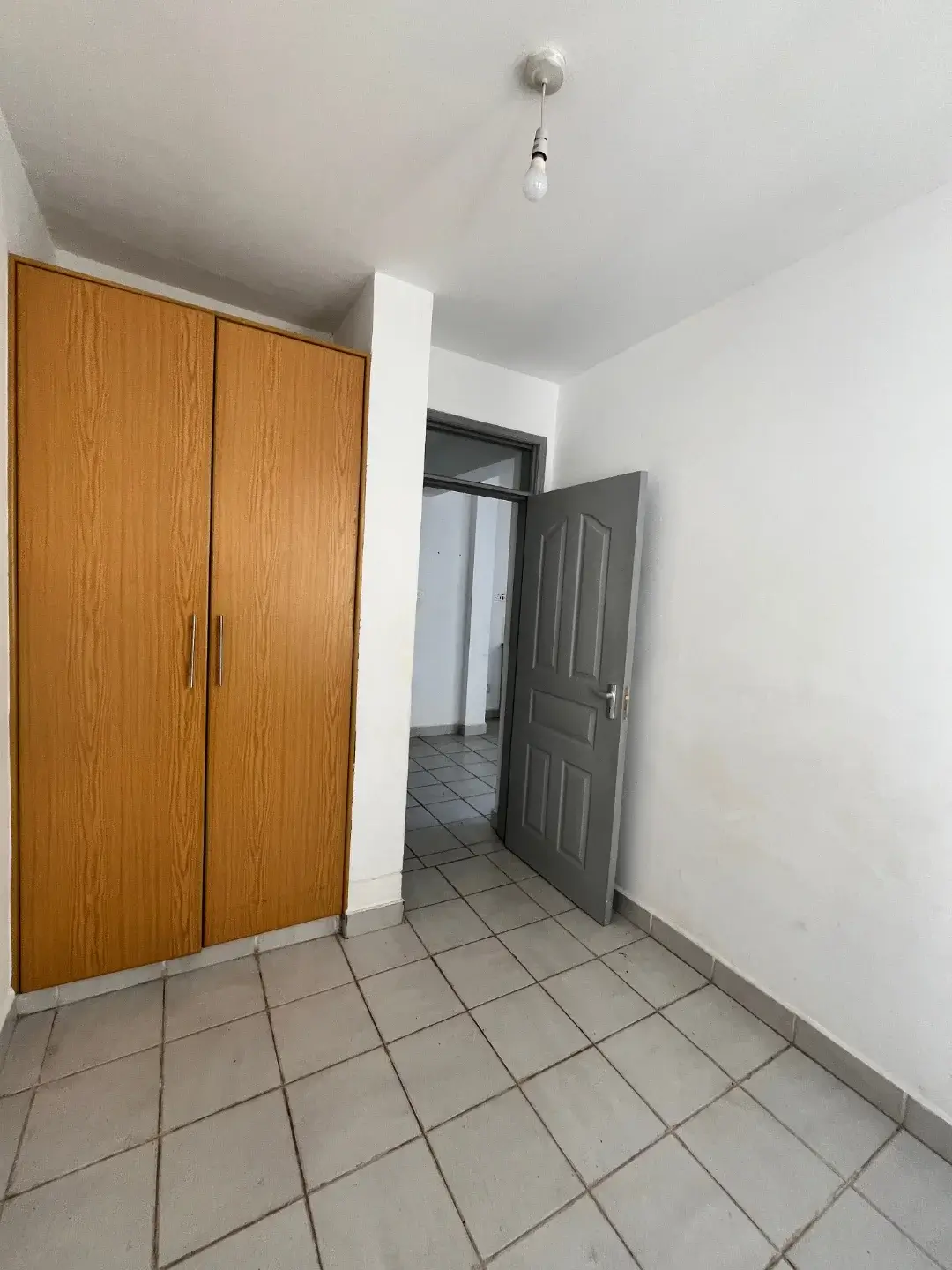 Spacious bedroom with wooden wardrobe and tiled flooring