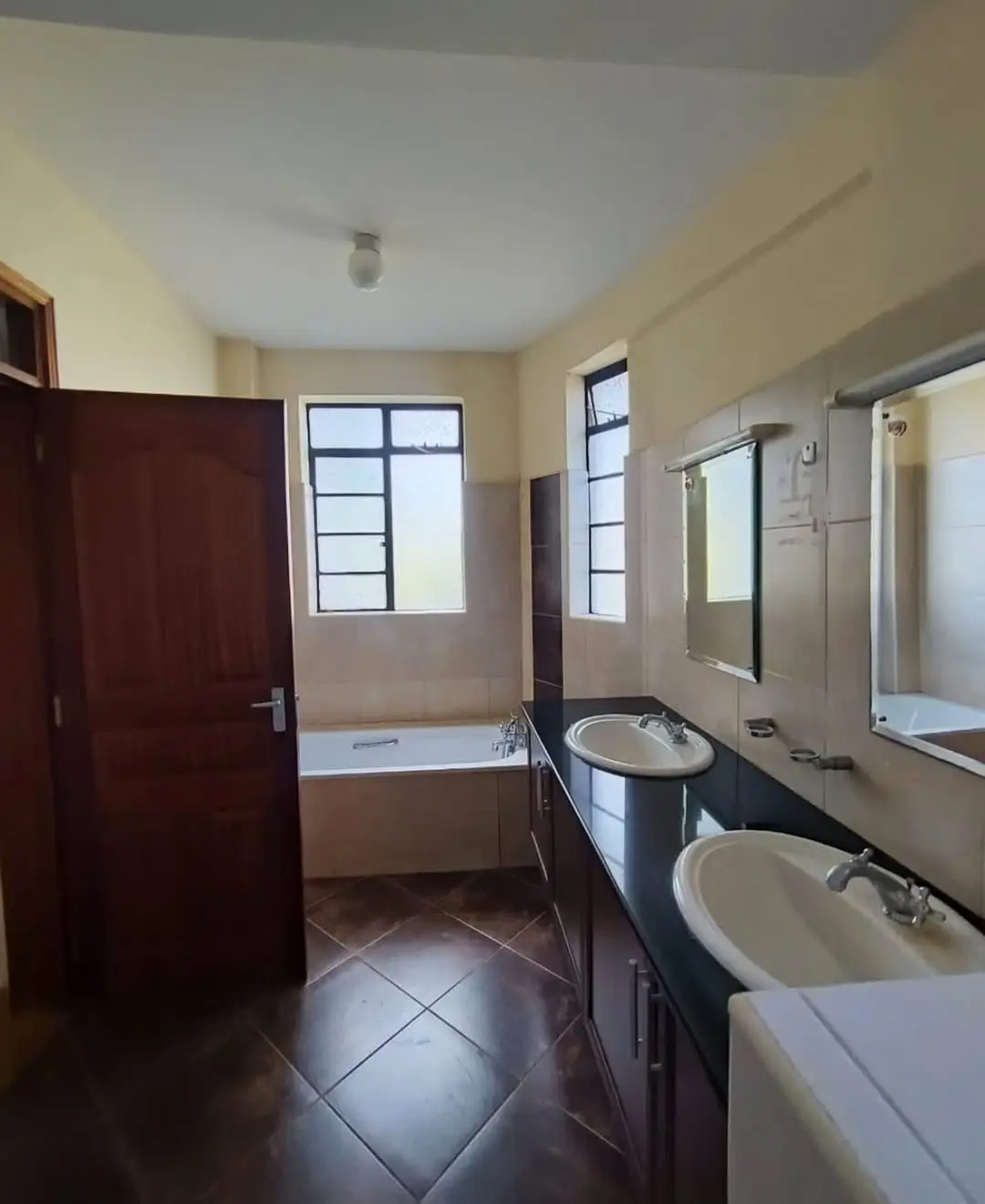 Spacious bathroom with dual sinks, bathtub, and large windows