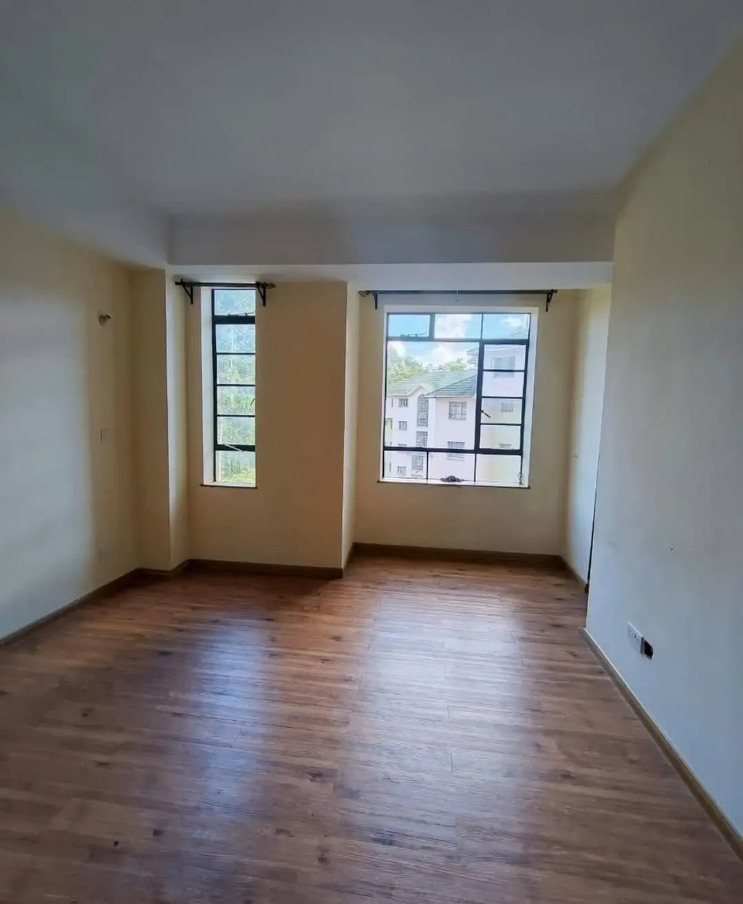 Spacious living room with wooden floors and dual windows