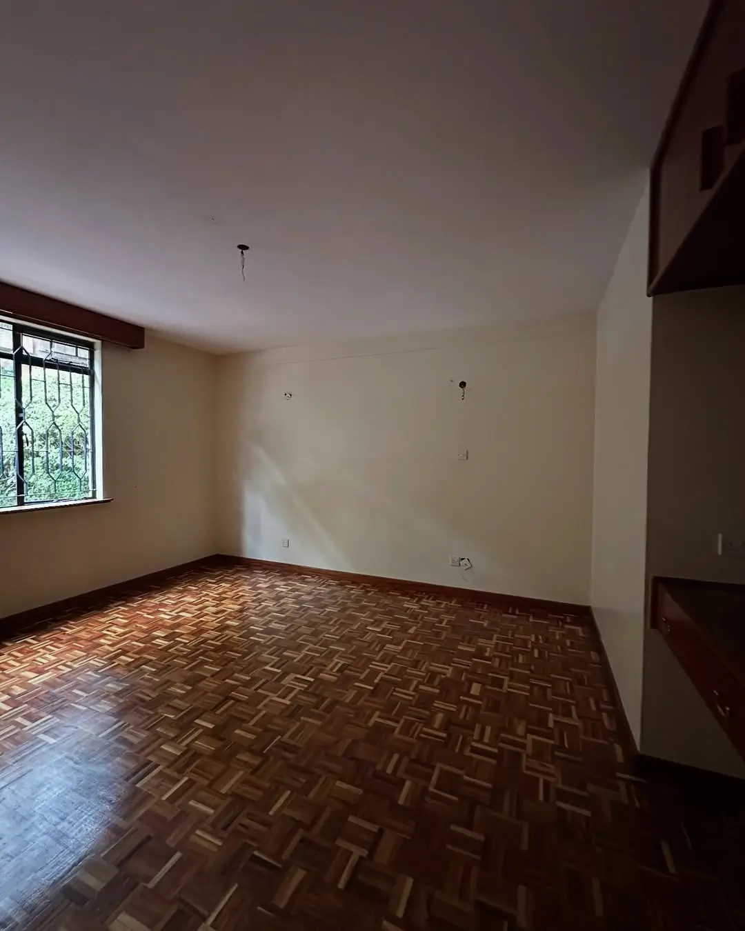 Empty bedroom with herringbone wooden floor and window