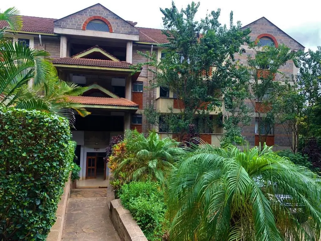 Multi-story brick building with manicured compound and palm trees