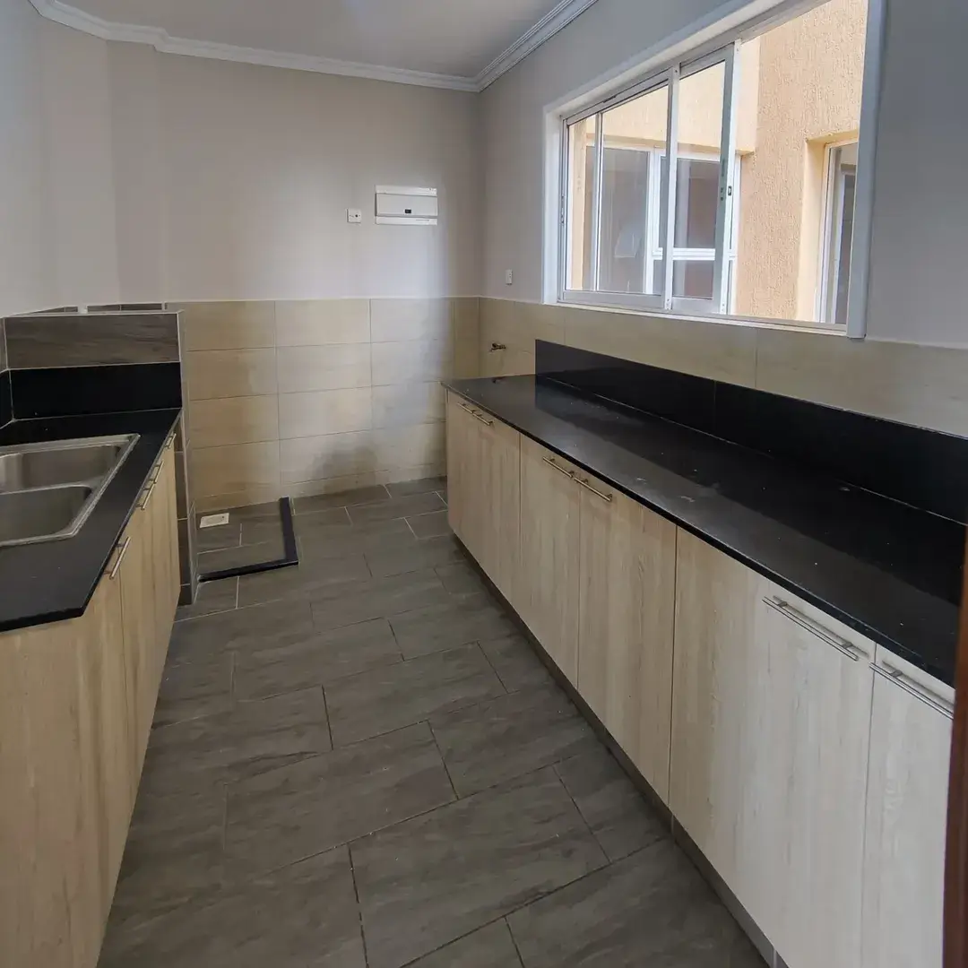 Galley kitchen with black countertops and light wood cabinets
