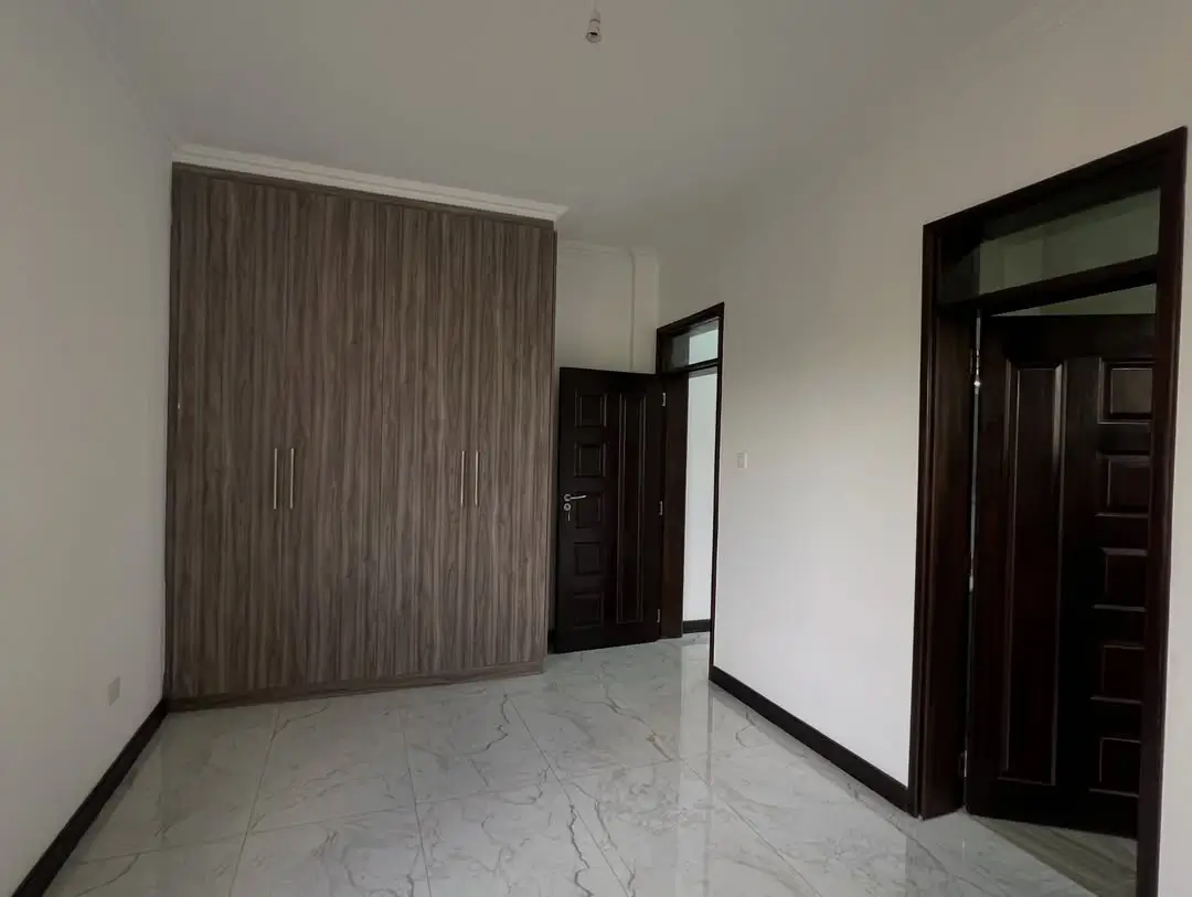 Empty bedroom with marble flooring and built-in wardrobe