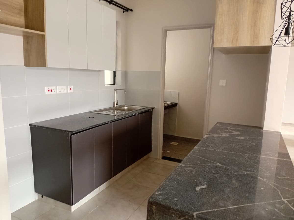 Modern kitchen with dark cabinetry, black countertops, white backtile