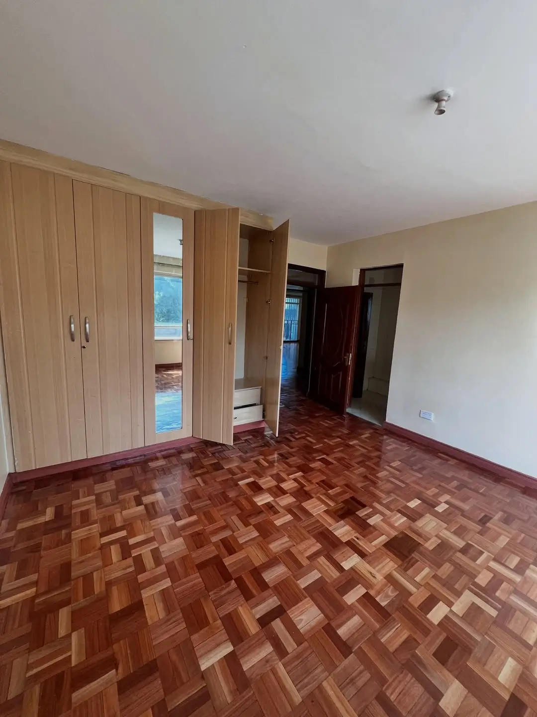 Spacious bedroom with wooden wardrobe and parquet flooring