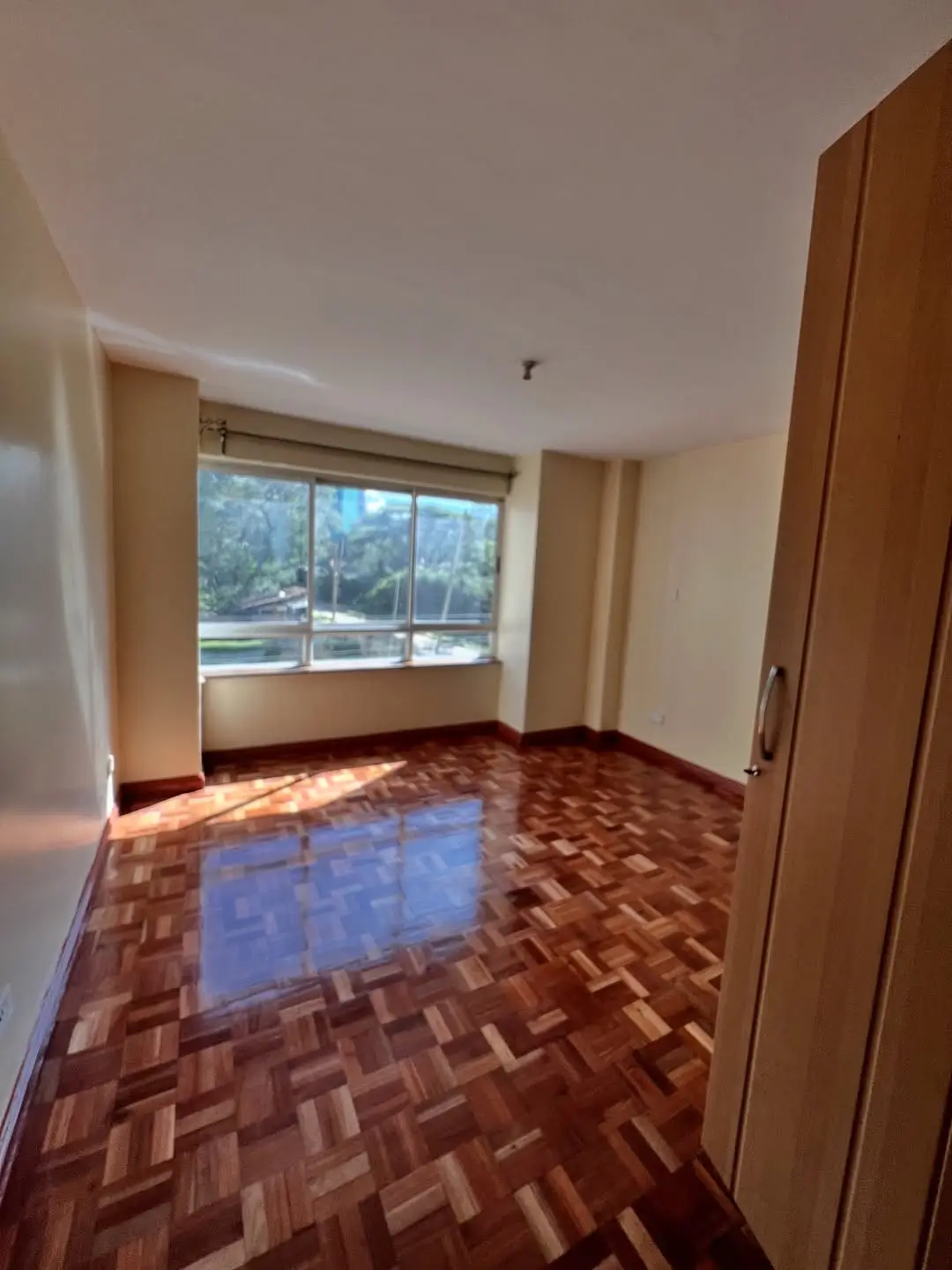 Spacious bedroom with large window overlooking landscaped grounds