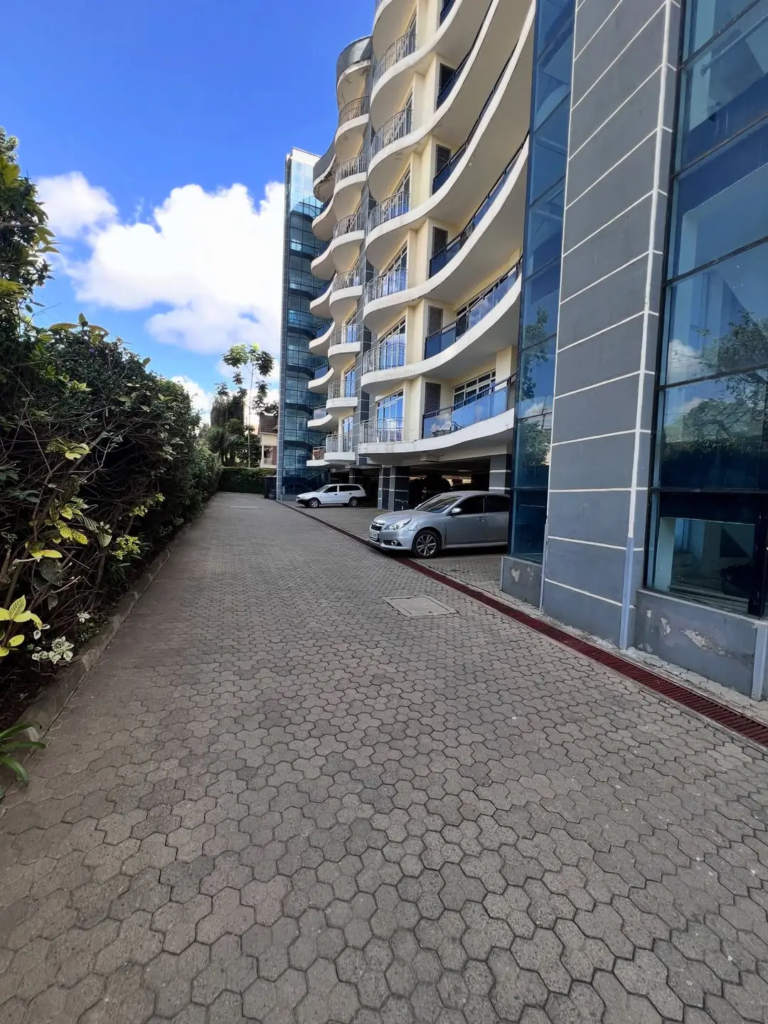 Modern curved residential building with ground-level parking bays